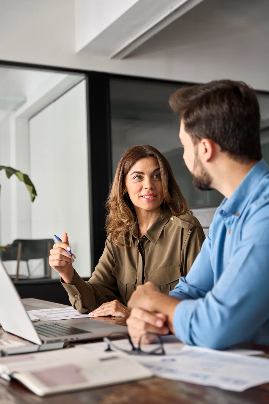 a man and a woman sitting at a table looking at a laptop