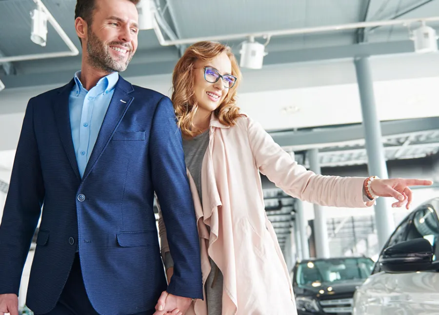 a man and a woman standing in front of a car