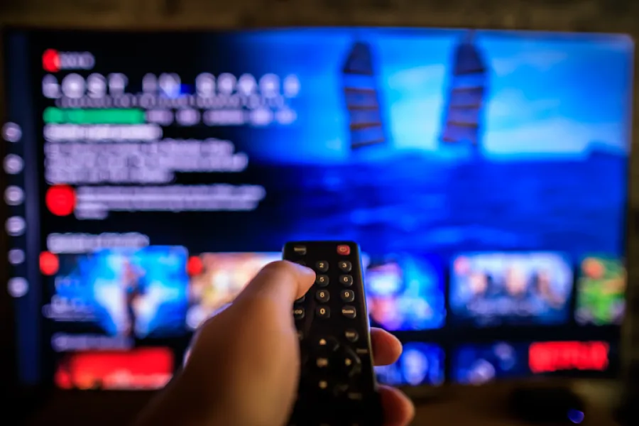a hand holding a remote in front of a television screen