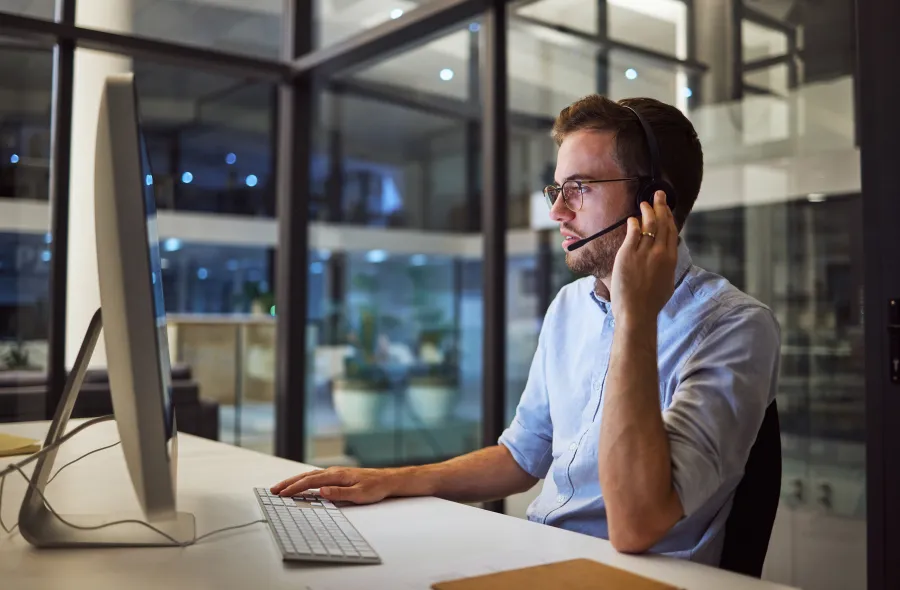 a man wearing headphones and sitting at a desk with a computer