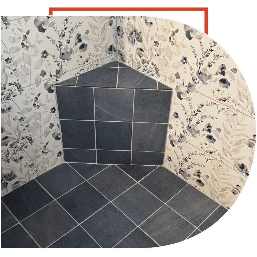 Corner wall with blue-grey tiles and floral wallpaper featuring beige and navy botanical patterns.