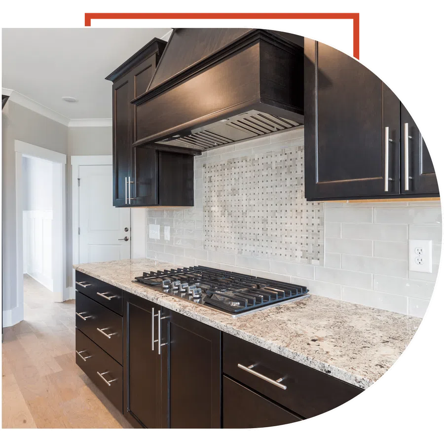 Modern kitchen with dark wood cabinets, granite countertop, stainless steel gas stove, and tiled backsplash.