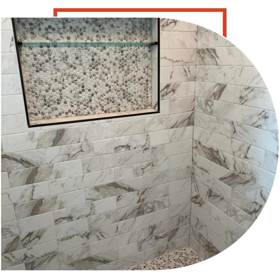 Marble-patterned subway tiles and pebble stone mosaic in a modern shower niche and floor corner