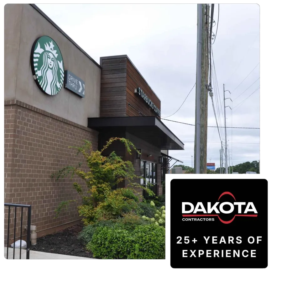 Exterior view of a Starbucks coffee shop with drive-thru sign and greenery under cloudy sky.