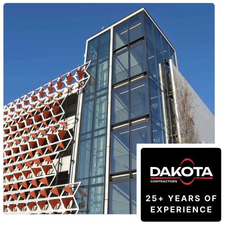 Modern building with glass panels and geometric red and white angular sunshades under clear blue sky.