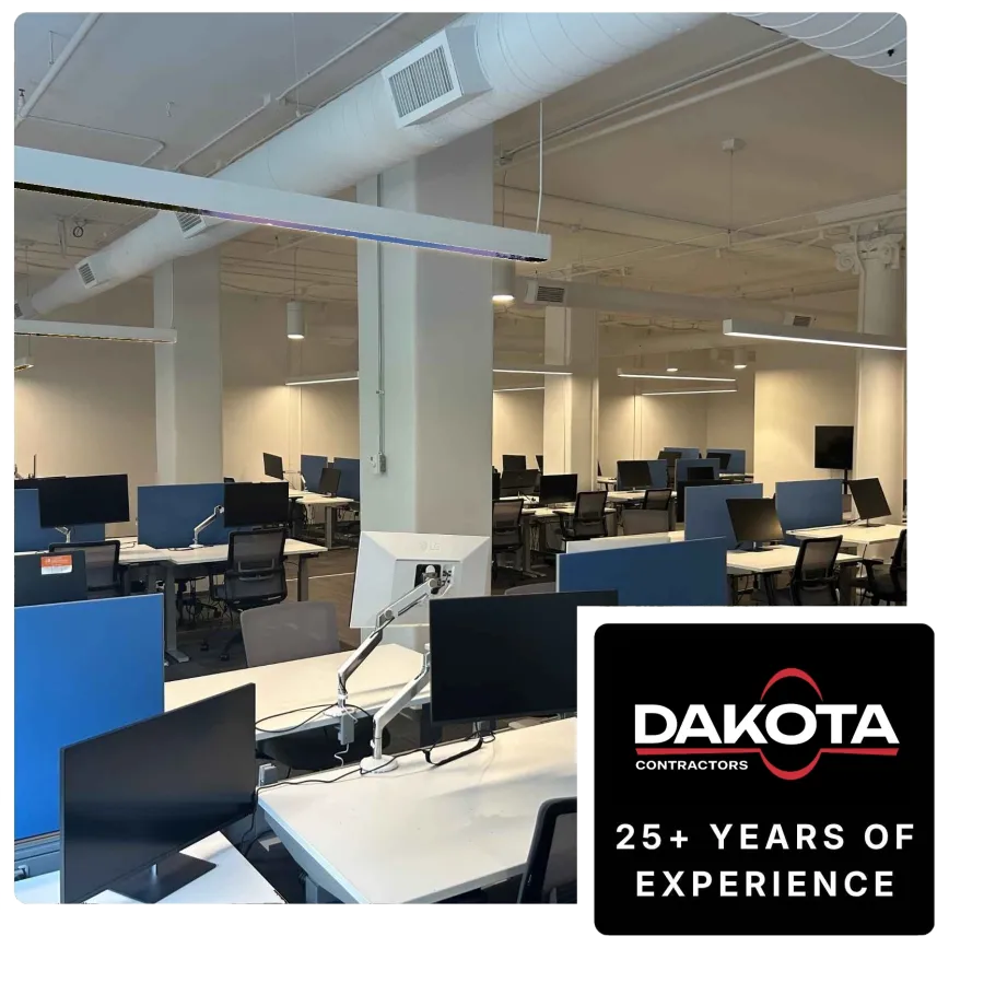 Modern empty office space with multiple desks, computer monitors, and seating in an open layout.