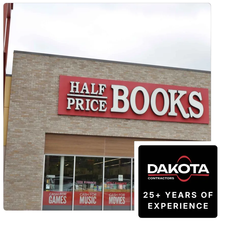 Storefront of Half Price Books with signs for cash for games, music, movies, and Dakota Contractors ad