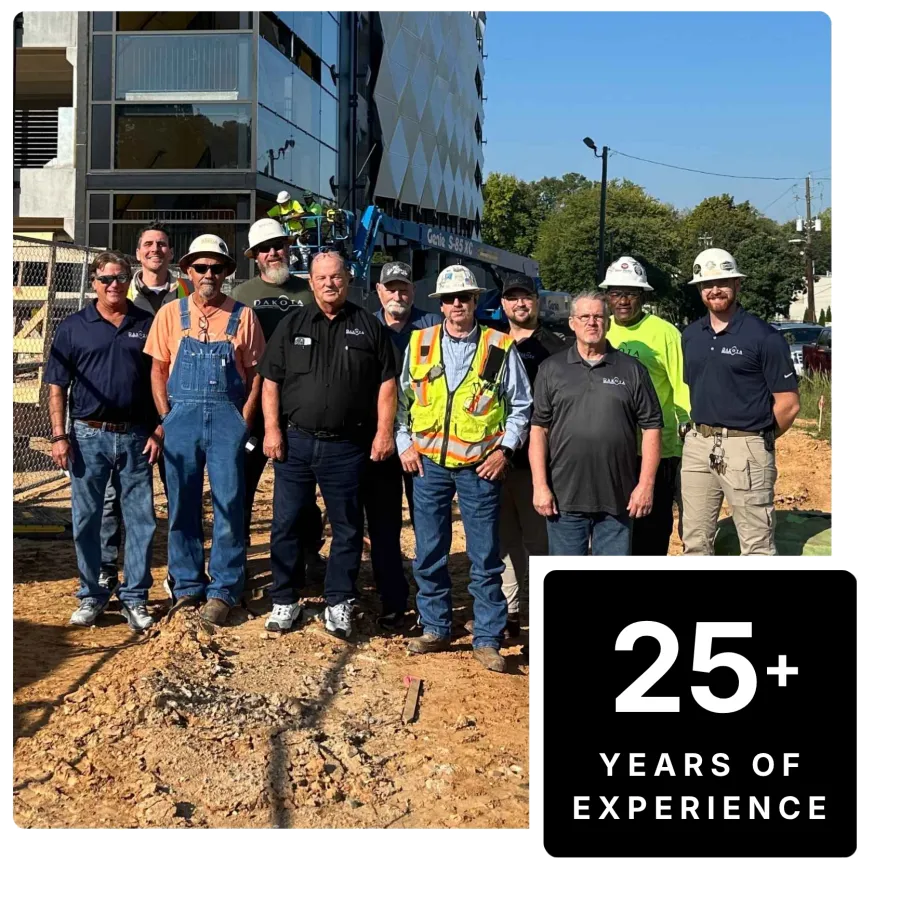 Construction team posing at building site with 25 plus years of experience badge in bright sunny weather.