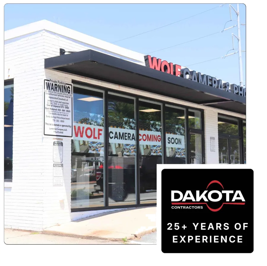 Storefront of Wolf Camera with signs reading coming soon and private parking warning on white brick building.