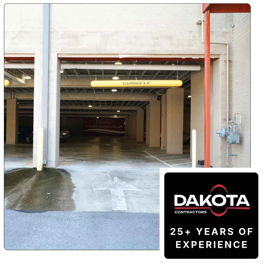 Entrance to an indoor parking garage with clearance sign and directional arrow on concrete floor.