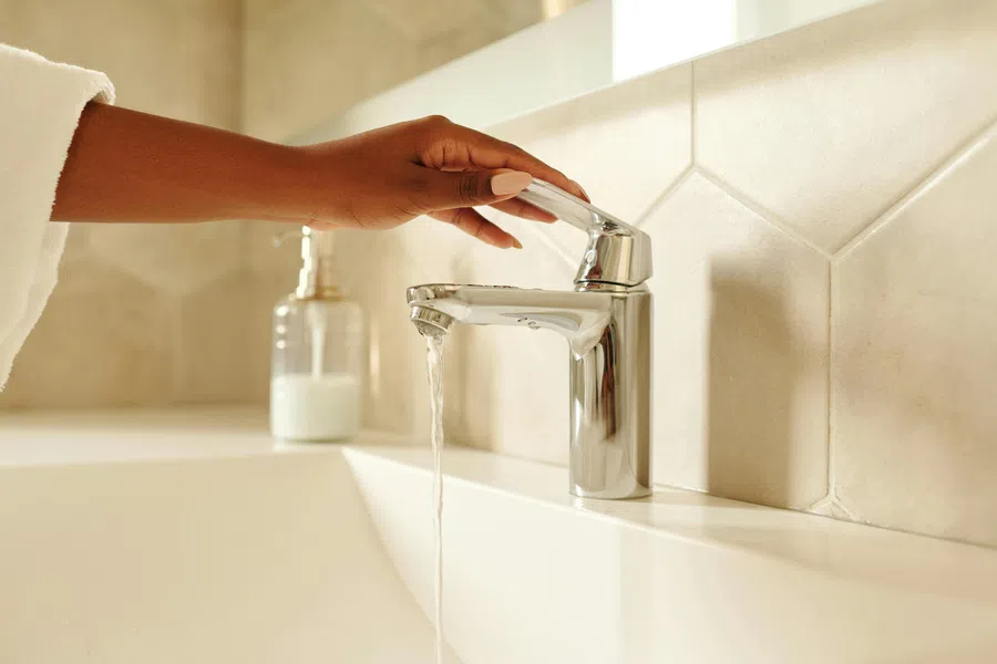 a hand pouring a liquid into a faucet