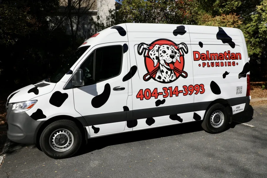 White plumbing van with Dalmatian dog logo and black spots, displaying Dalmatian Plumbing and phone number 404-314-3993.