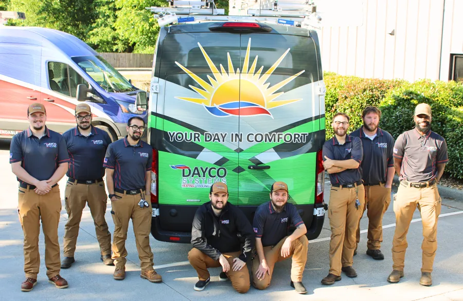 Dayco Systems team posing in front of branded service vans with slogan Your Day in Comfort outdoors