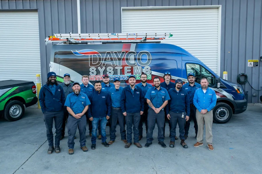 Team of Dayco Systems HVAC technicians standing in front of a branded service van at a warehouse.