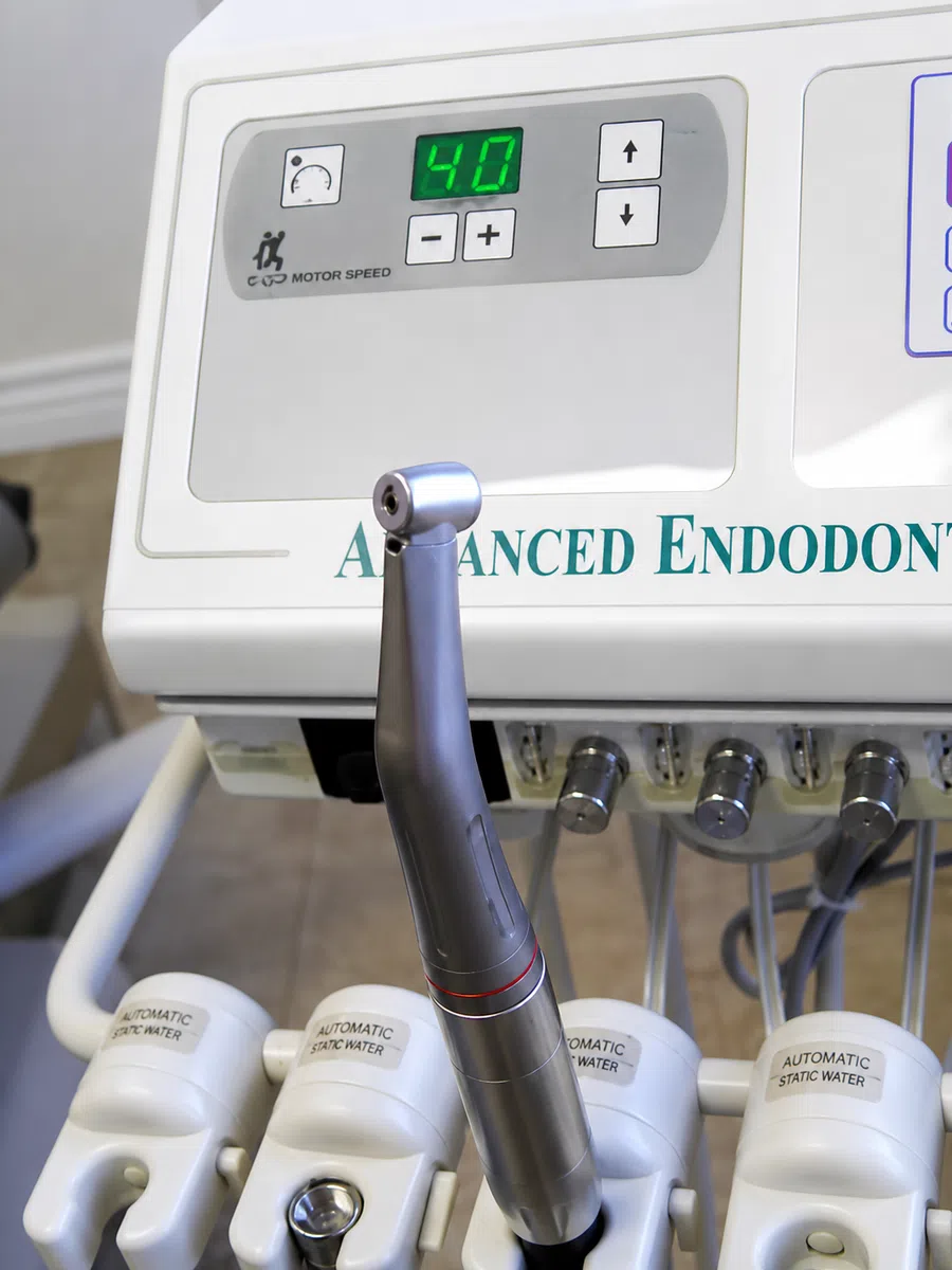 Close-up of dental endodontic handpiece and control panel showing digital display and tool holders.