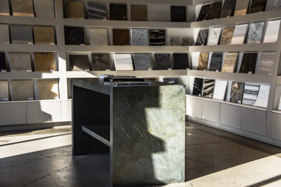 Modern showroom featuring a green stone table and a display of various wall tiles and materials.