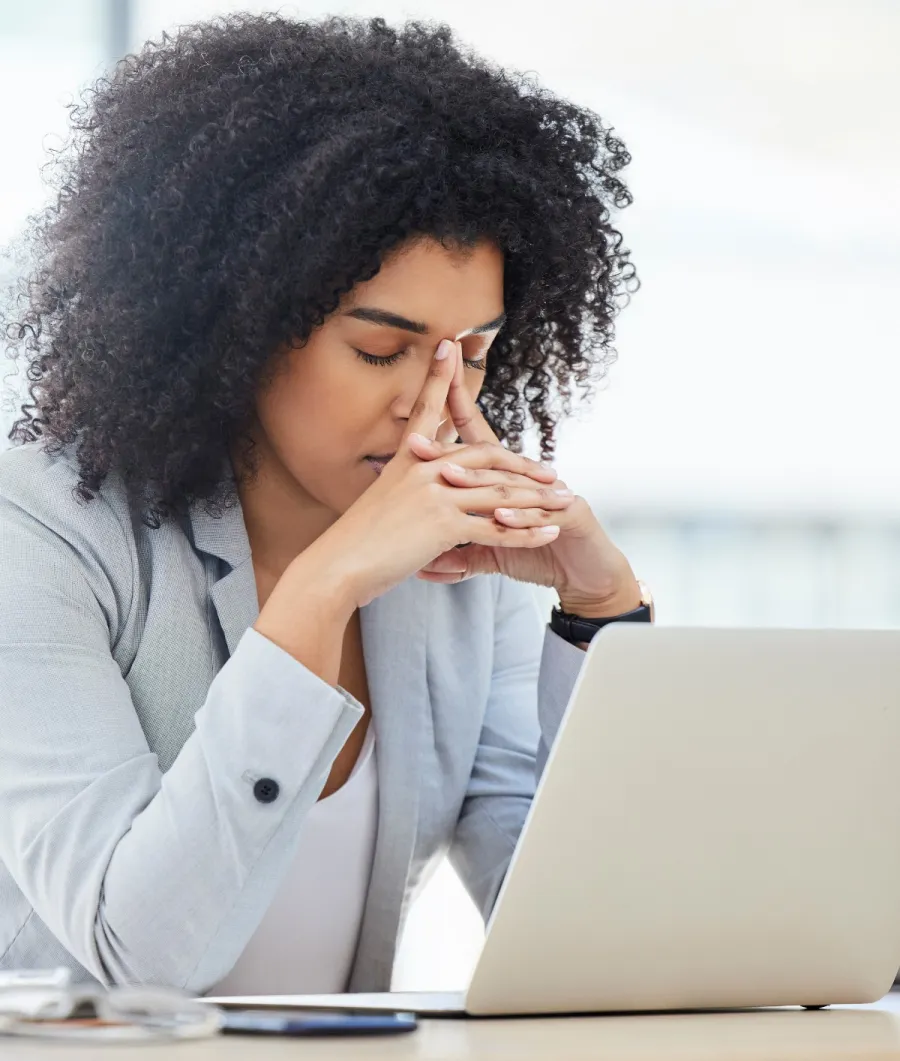 a woman with her hand on her face looking at a laptop