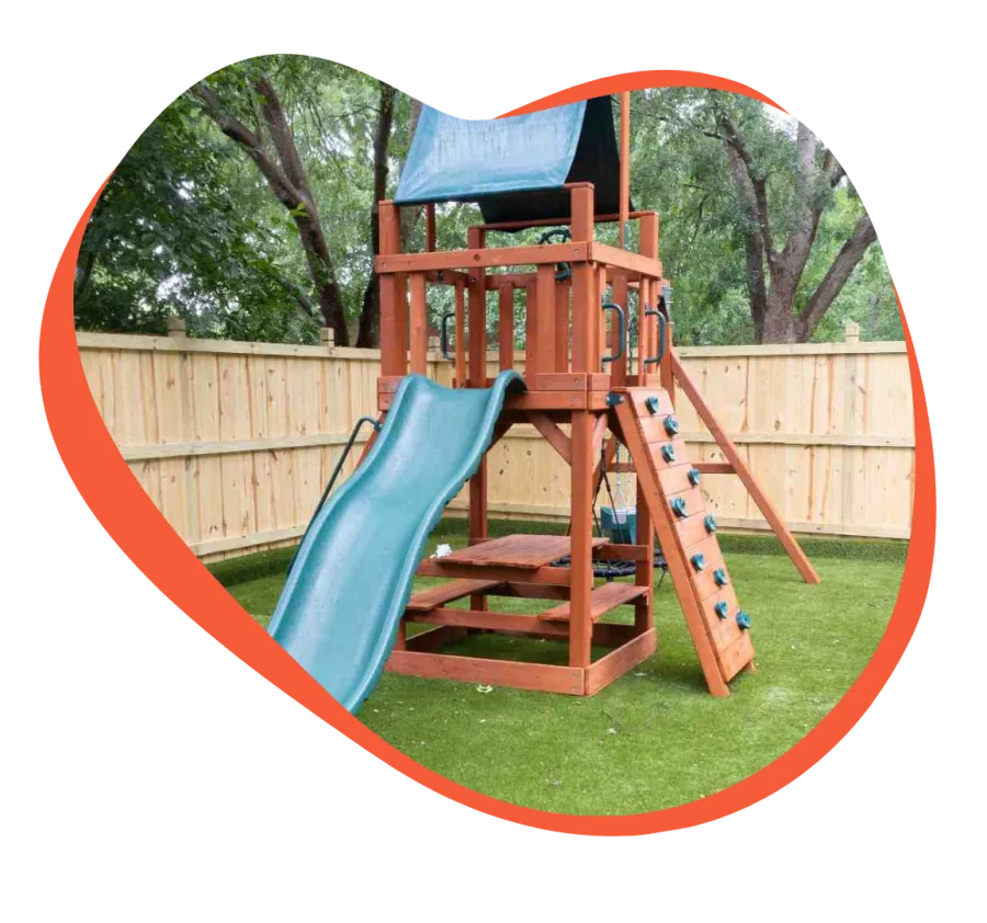 Wooden backyard playground set with blue slide, climbing wall, and swing under a blue canopy.