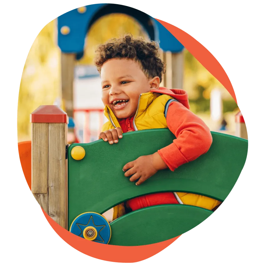 a boy in a yellow and red playground toy