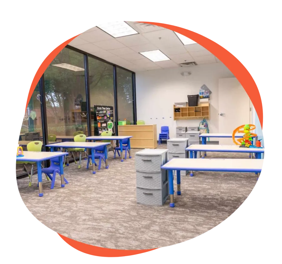Bright and organized classroom with blue tables, green and blue chairs, and large windows letting in natural light