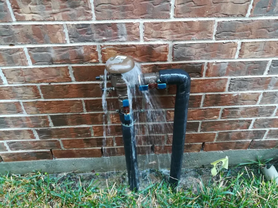 a metal pipe in front of a brick wall