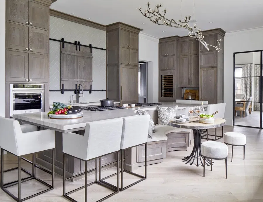 Modern kitchen with gray cabinetry, built-in appliances, large island, breakfast nook, and contemporary lighting fixture