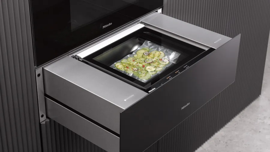 Modern Miele kitchen appliance cooking vacuum-sealed food in a sleek stainless steel drawer oven.