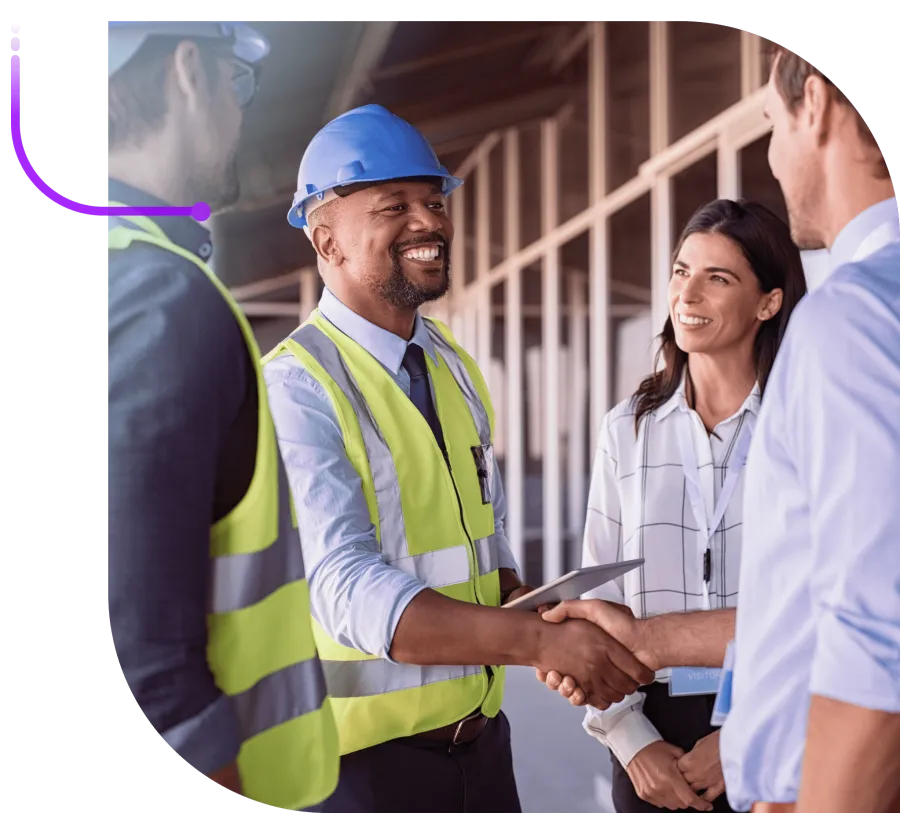 Construction manager in safety gear shaking hands with businesspeople at a building site meeting