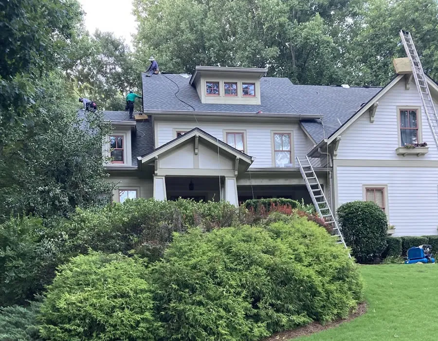 a house with a ladder and bushes in front of it