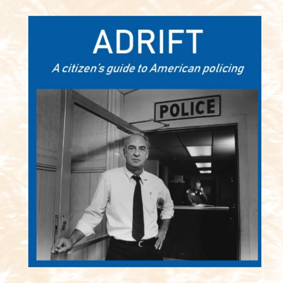 Black and white photo of a man in a tie standing in front of a police station entrance under a POLICE sign