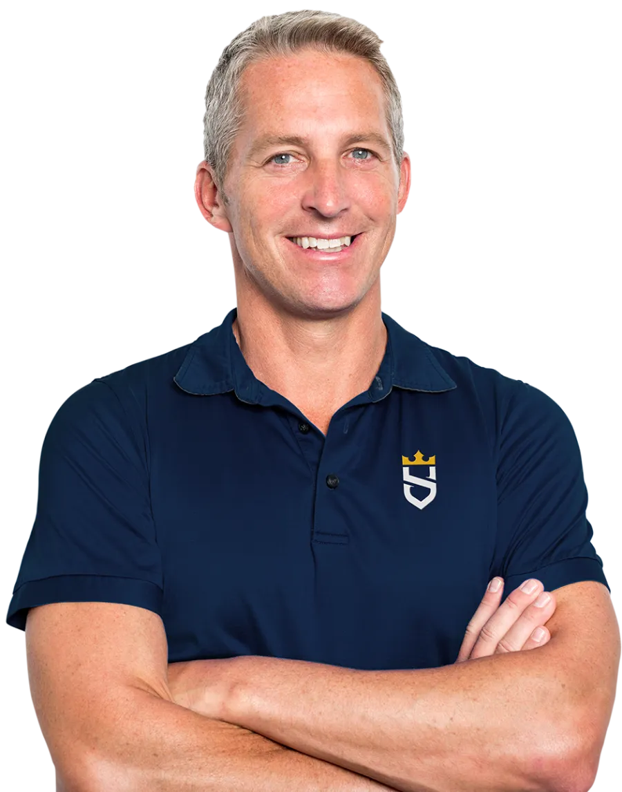 Smiling man with crossed arms wearing navy blue polo shirt with a white and gold emblem on chest.