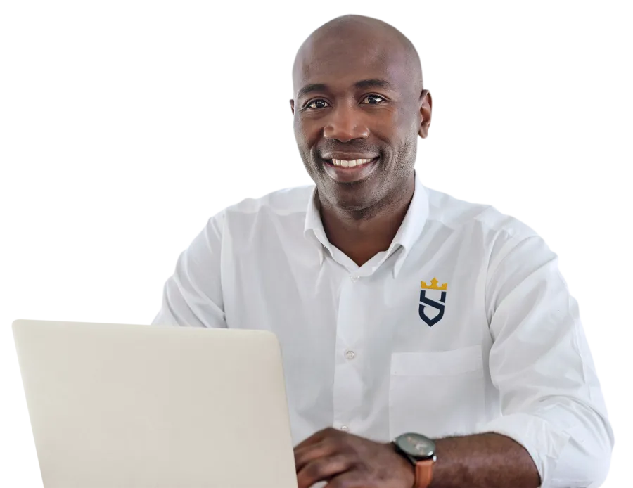 A man in his thirties sitting at a laptop, smiling, looking at camera with white button-down Sir Grout shirt