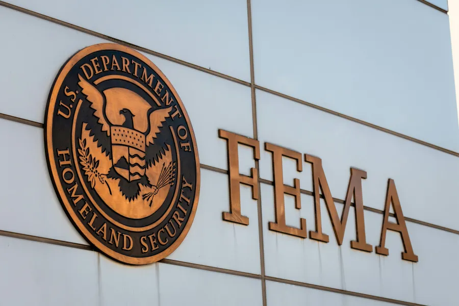 Exterior sign of the U.S. Department of Homeland Security FEMA office featuring the official seal and large letters on a white wall.