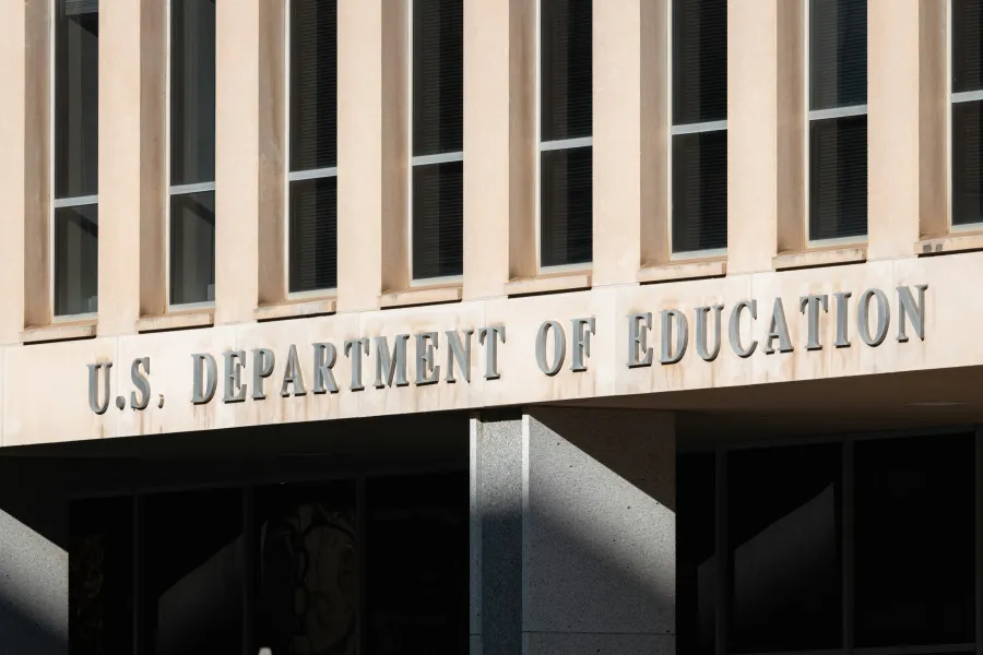 Facade of the U.S. Department of Education building with large metal lettering and vertical windows.