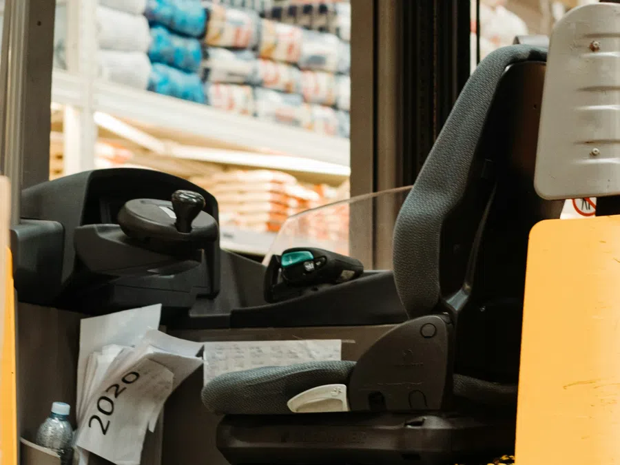 Close-up of a Jungheinrich forklift operator seat inside a warehouse with stacked goods in background.