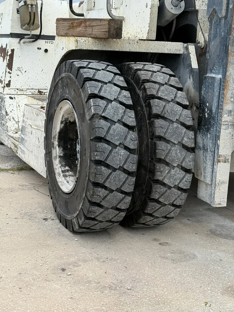 Close-up of dual heavy-duty tires on an industrial forklift with rugged tread patterns on concrete ground.