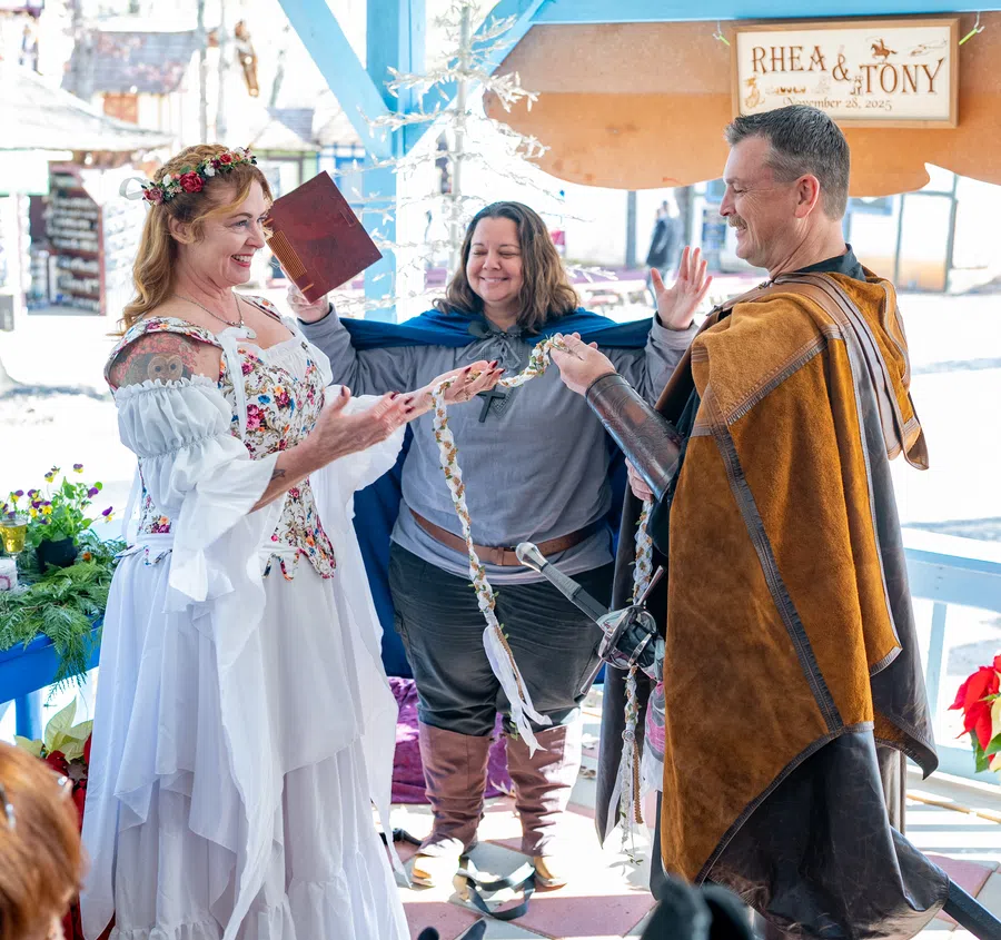 A couple joined by a handfasting cord as the Festival officiant leads their ceremony