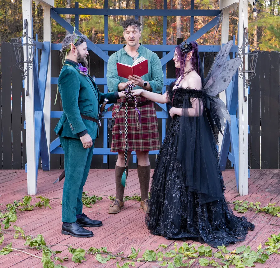 A couple's hands are bound with a handfasting cord by the Festival officiant