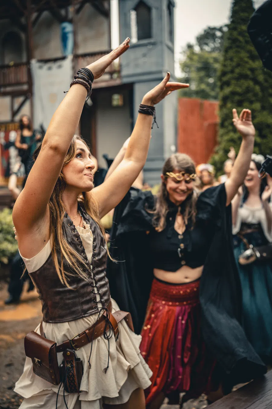 Women dancing with their arms raised in the Festival village.