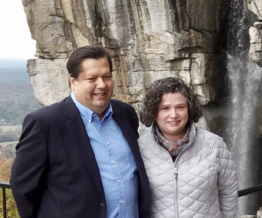 a man and woman standing in front of a rock wall