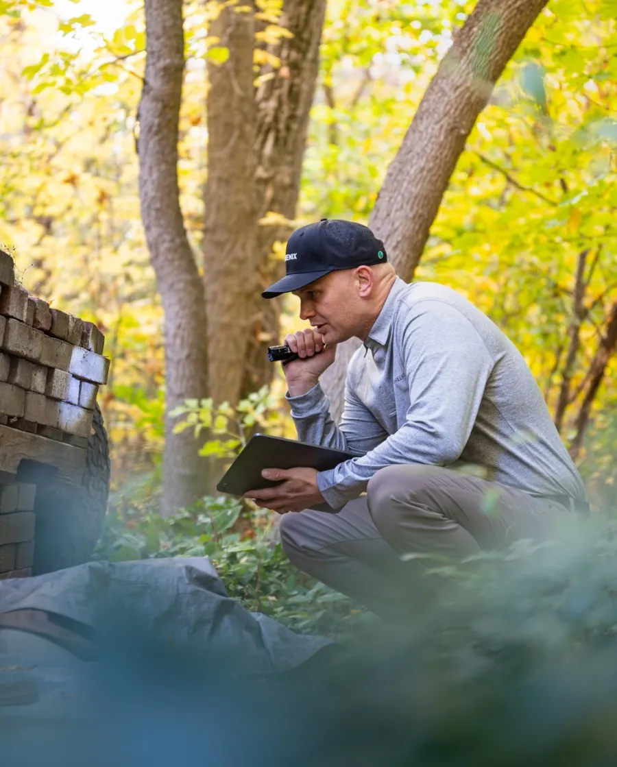 a man sitting on a log with a phone in his hand