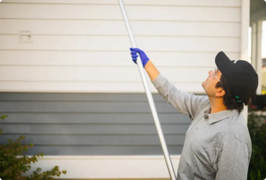 a person using a broom to dust a roof