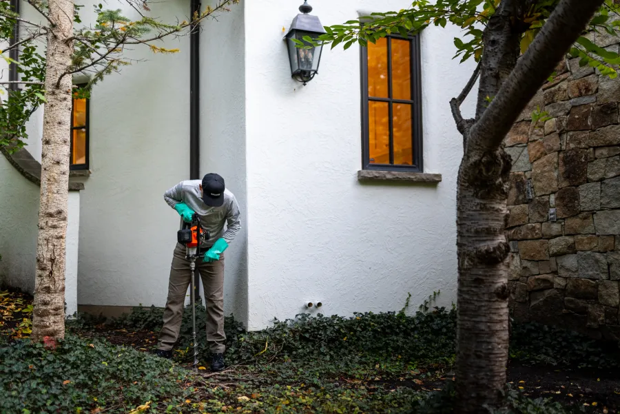 a person with a mole extraction tool outside a house