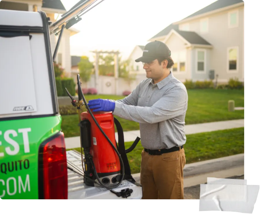 Pest control worker wearing gloves preparing spray equipment from truck in suburban neighborhood