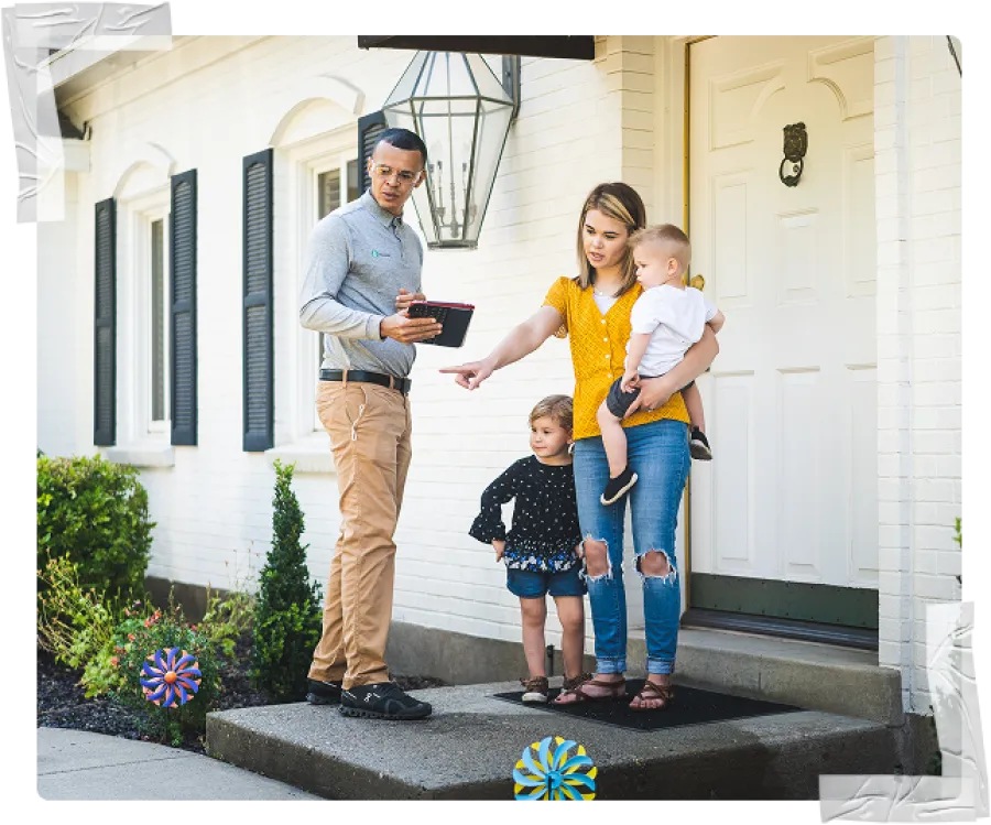 Realtor showing a house on tablet to mother with two young children outside a white brick home.