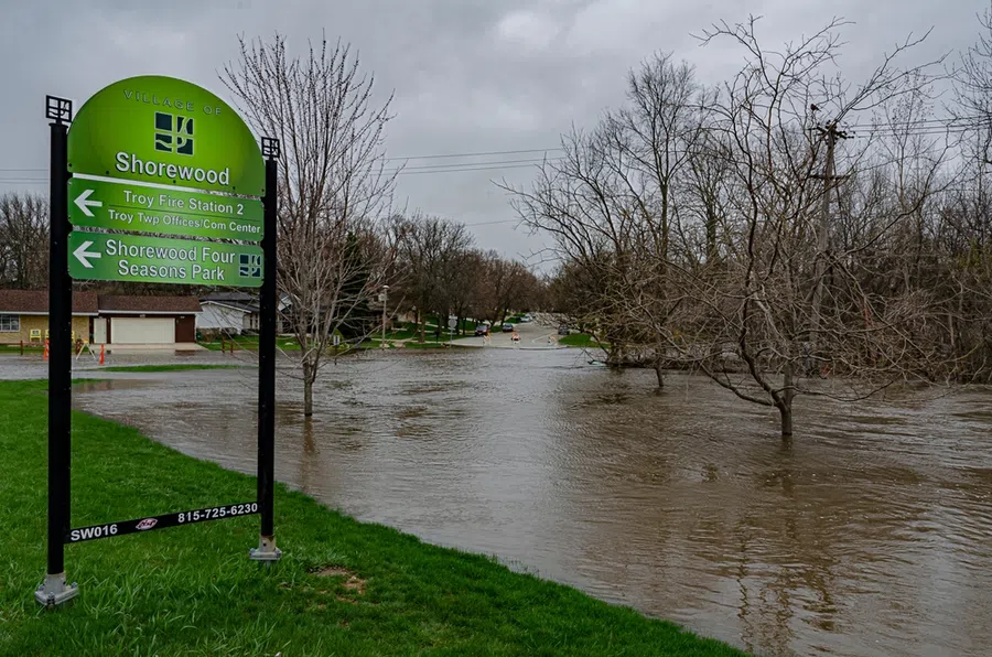Flooded street in Shorewood with water covering road and leafless trees under overcast sky