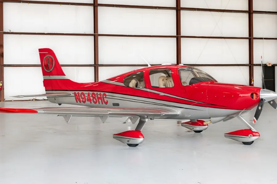 Red and silver single-engine private airplane in a spacious hangar with registration N948HC visible.
