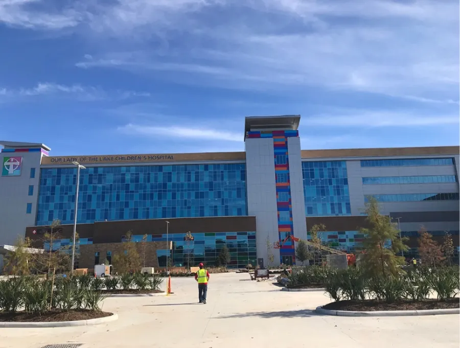 Exterior view of Our Lady of the Lake Children's Hospital with blue glass windows under a clear sky.