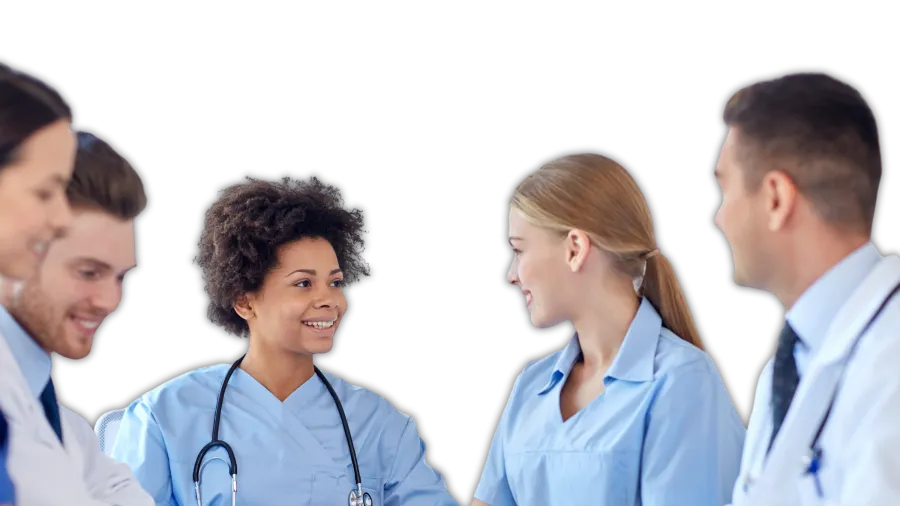 Group of diverse healthcare professionals in scrubs and lab coats discussing and smiling in a medical setting.