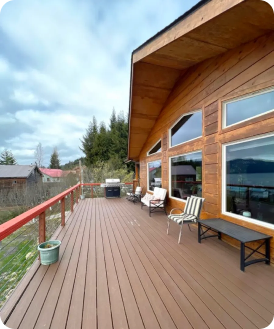 a deck with chairs and tables on it next to a building